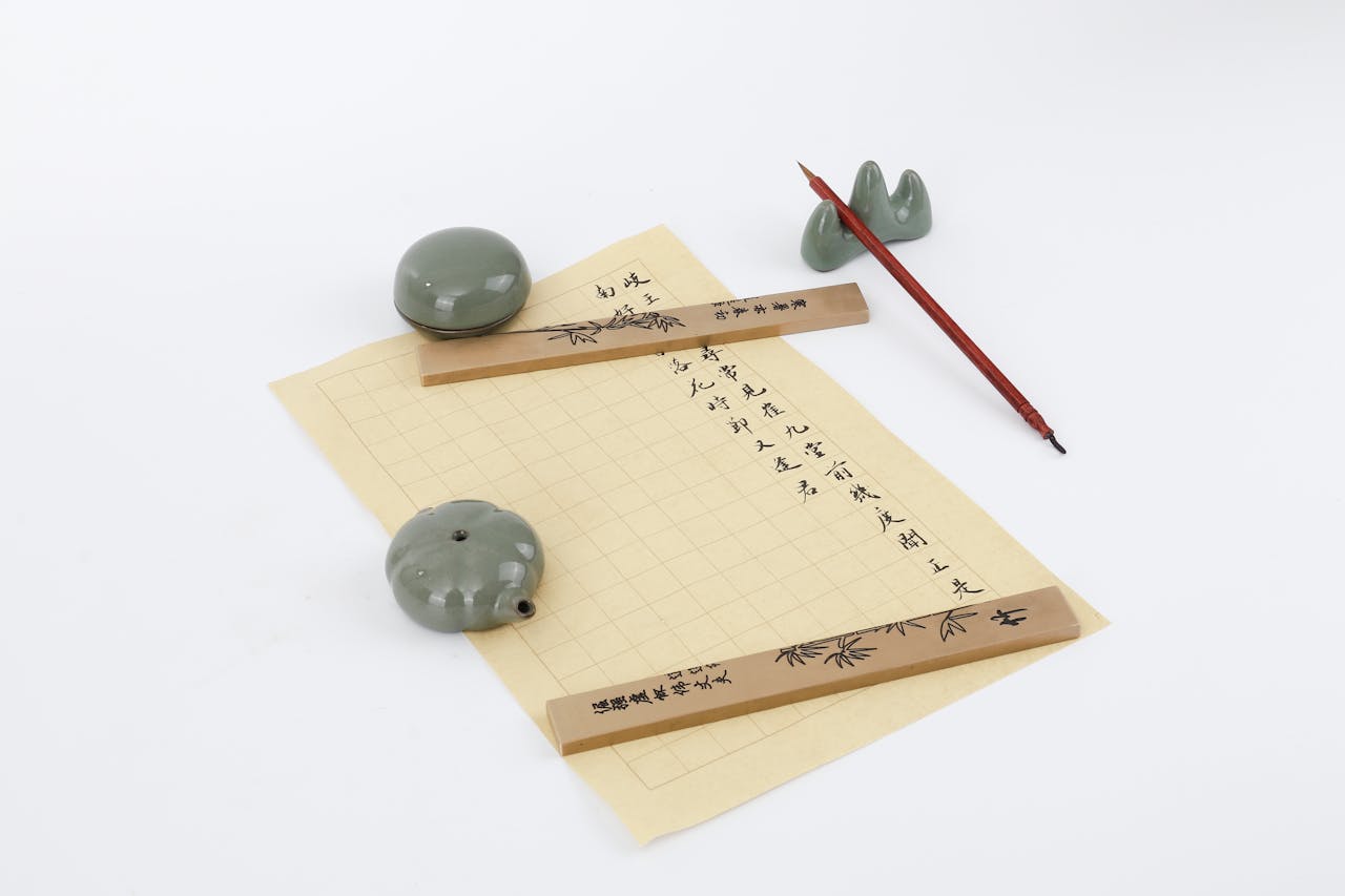Flat lay of a traditional Chinese calligraphy set with brush, paper, and ink stones on a white background.