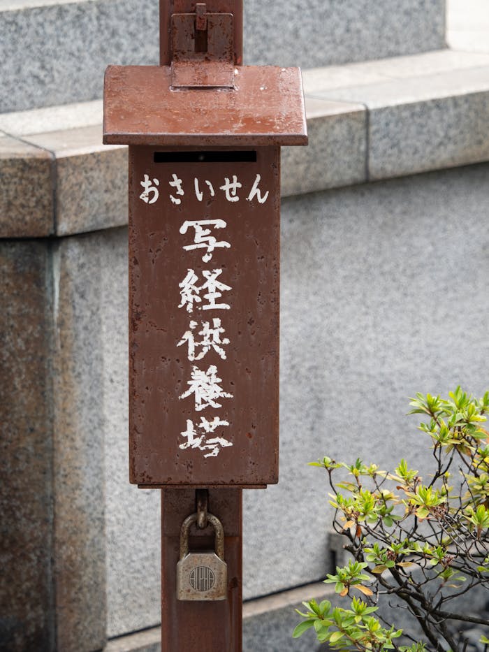 Rustic Japanese mailbox with kanji, captured in Tokyo street, offers a glimpse of urban culture.