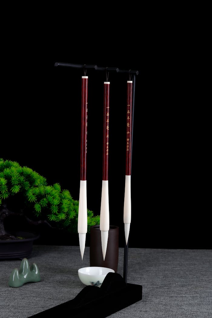 A sophisticated set of hanging calligraphy brushes with a bonsai backdrop, perfect for artistic inspiration.
