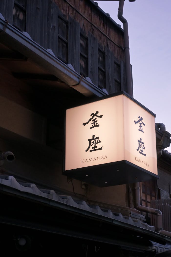 Illuminated lantern with Kanji script at twilight on a traditional Japanese building
